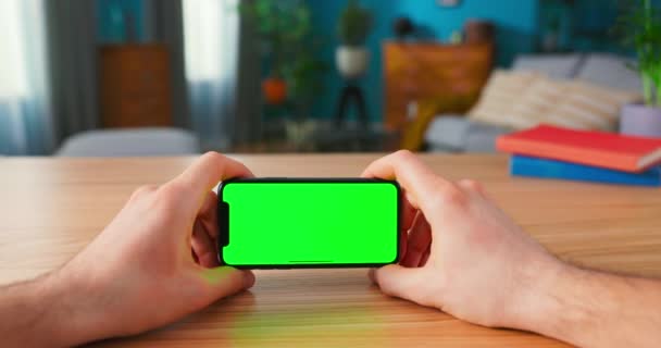 Primer plano del hombre usando Green Mock-up Screen Smartphone en modo paisaje mientras está sentado en su — Vídeos de Stock