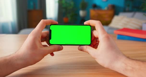 Κοντινό πλάνο του ανθρώπου χρησιμοποιώντας πράσινο mock-up οθόνη Smartphone σε λειτουργία τοπίου, ενώ κάθεται στο του — Αρχείο Βίντεο