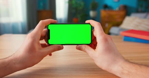 Primer plano del hombre usando Green Mock-up Screen Smartphone en modo paisaje mientras está sentado en su — Vídeos de Stock