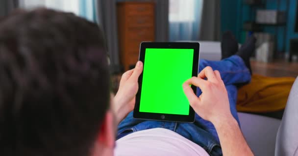 Student jongen rusten op een bank met behulp van met groene Mock-up Screen Tablet Computerin verticale Portret — Stockvideo
