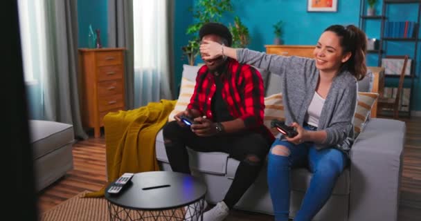 Glada blandraser par afroamerikanska Man och kaukasisk kvinna vilar i rummet sitter på soffan — Stockvideo