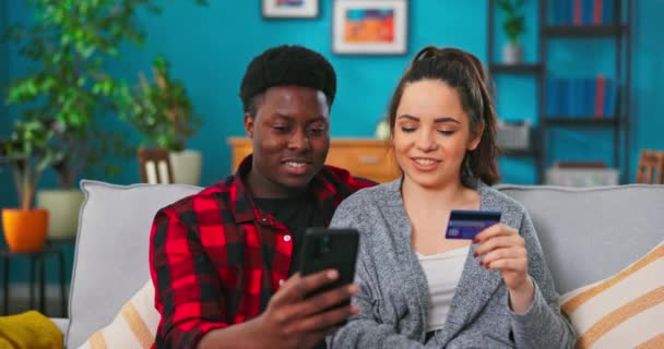 Portrait de joyeux jeune couple homme et femme assis sur le canapé dans le salon faisant du shopping — Video