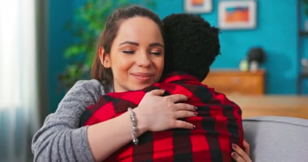 Sonriente feliz pareja africano hombre y americano mujer chica abrazando mientras sentado en sofá en — Vídeo de stock