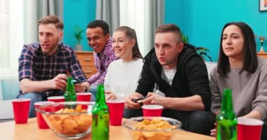 Bir grup arkadaş evde video oyunu oynuyor, eğleniyorlar. Gülümseyen bir adam yarışıyor