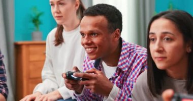 Siyah Afro-Amerikalı heyecanlı bir adam kanepeye oturmuş, elinde bir joystick, video oyunları oynuyor,