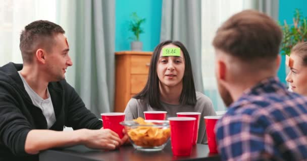 En la sala de estar Diverso grupo de amigos cariñosos divertidos jugando ¿Quién soy? juego — Vídeos de Stock