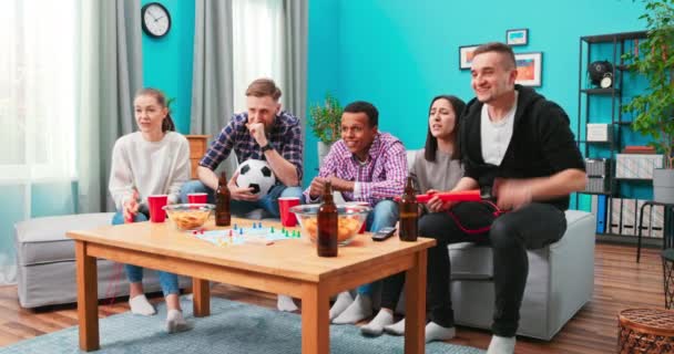 Fósforo perdido. Amigos molestos viendo fútbol y bebiendo en casa sentados en un sofá. Estudiantes — Vídeos de Stock