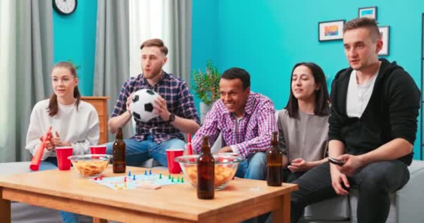 一群多种族的朋友在家里看电视上的体育比赛,玩得很开心.人 — 图库视频影像