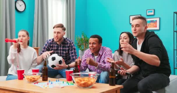非常兴奋的朋友们通过观看足球比赛和在家里和室内吃饭来开心。友谊, — 图库视频影像