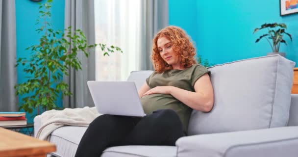 Attraktive, fürsorgliche werdende Mutter, schwangere Frau, die sich ausruht, entspannt auf dem Sofa im Wohnzimmer, — Stockvideo