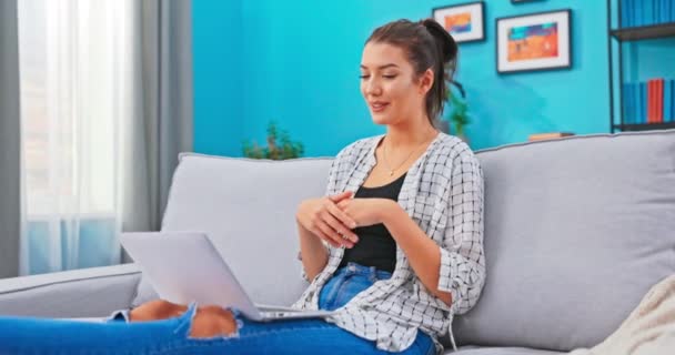 Kapcsolat nő ül a kanapén a nappaliban, és tartja a laptop, számítógép — Stock videók