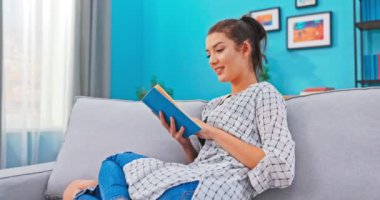 Saçları tokalı güzel bir kadın. Sade kıyafetlerle rahatlıyor. Kitabın içini kurcalıyor.