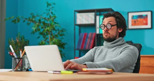 Hombre raro trabaja delante de la computadora, escribe correos electrónicos a los clientes, grifos en el ordenador portátil — Vídeos de Stock