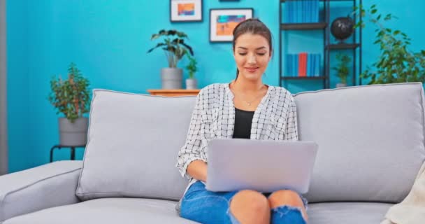 Den unga affärskvinnan arbetar långt hemifrån, i vardagsrummet på soffan, håller laptop — Stockvideo