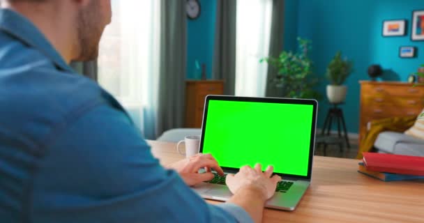 Över axeln skott av män händer Skriva på en bärbar dator med grön modell Skärm. — Stockvideo