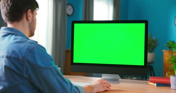 Man Använder allt i en dator med grön Mock-up skärm medan du sitter vid skrivbordet — Stockvideo