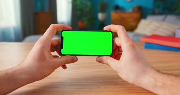 Close-up of Man Using Green Mock-up Screen Smartphone in Landscape Mode while Sitting at His — Stock Video