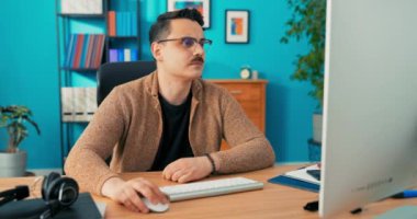 Odaklanmış genç işadamı masasına oturmuş kameraya bakıyor, ciddi profesyonel analist erkek.