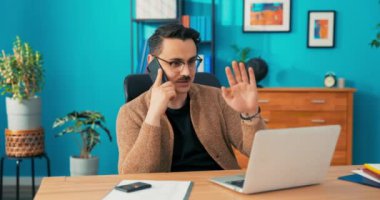 Yönetici dizüstü bilgisayarın önünde oturuyor cep telefonuyla hoş bir iş görüşmesi yapıyor. Başarılı.