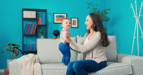 Kleines Mädchen mit großen, schönen Augen, süßes Baby steht auf Sofa neben Mama, — Stockvideo