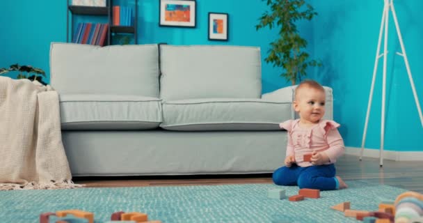 Mädchen mit schönen Augen spielt allein mit Klötzen auf Teppich im Wohnzimmer, findet Faden — Stockvideo