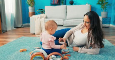 Akıllı küçük kız halının üzerinde oturuyor. Güzel anne, birlikte oynuyorlar.