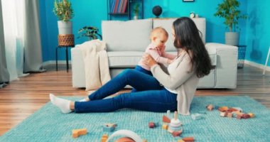 Akıllı küçük kız halının üzerinde oturuyor. Güzel anne, birlikte oynuyorlar.