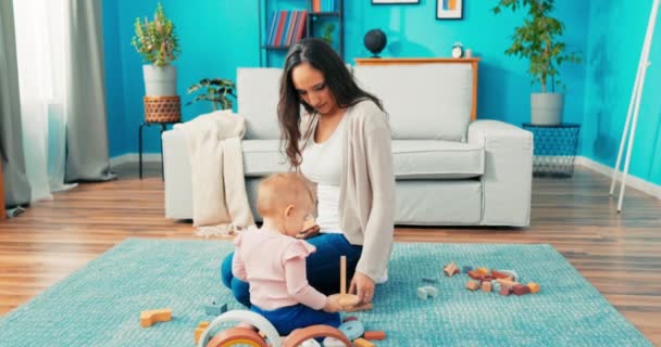 Krásná brunetka oblečená v džínách a svetr relaxuje doma sedí na koberci s — Stock video