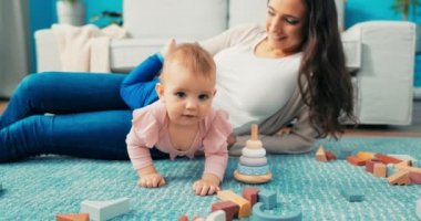 Uzun kahverengi saçlı çekici olgun bir anne oturma odasında yerde uzanıyor ve onunla konuşuyor.