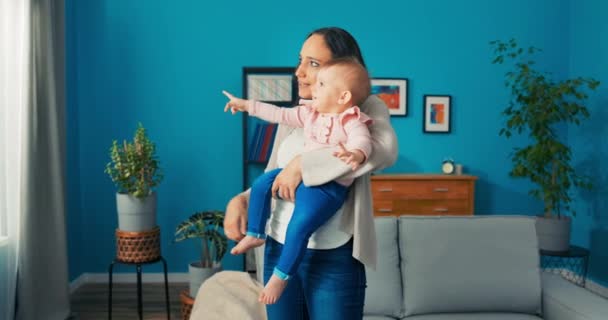 Vol kracht moeder houdt kind in armen gericht venster, punten met vinger in de voorkant — Stockvideo