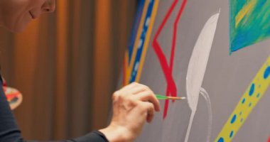 Ressam tuval ile sehpaya yakın duruyor, sürekli ince bir çizgiye bakıyor.