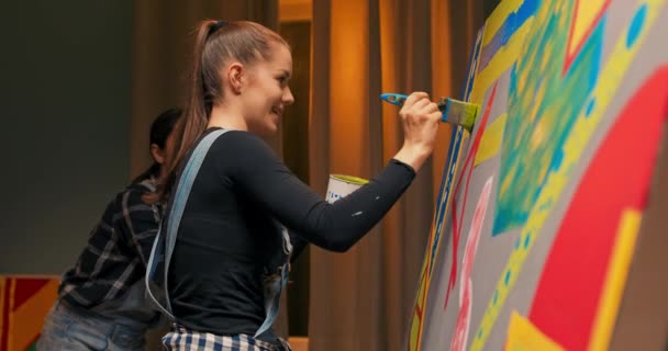 Amis drôles, farceurs, après les heures de cours en soirée assis en studio et retravailler la peinture collègues — Video