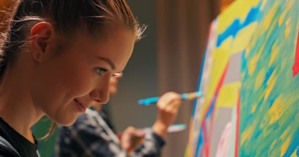 Talentvolle schilders bereiden werk voor op een ateliertentoonstelling, schilderen een beeld op een groot doek, — Stockvideo