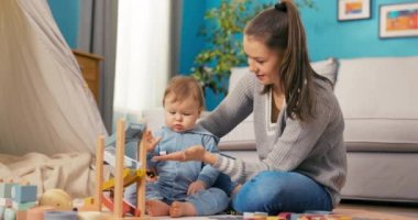 Sevecen, güzel bir kadın tatlı bir bebekle oynuyor.