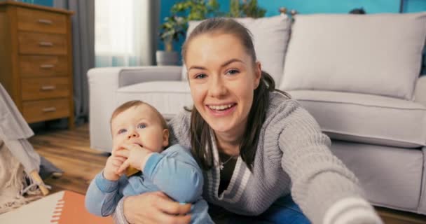 Mooie vrouw met bruin haar, influencer, blogger records video, vlog met schattige kleine zoon gekleed — Stockvideo