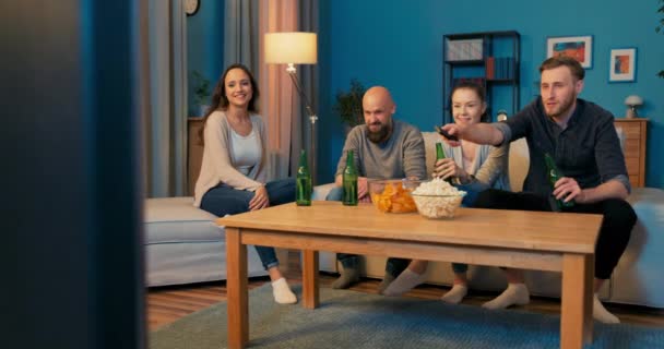 Czterech dobrych przyjaciół spędza wieczór w swoim towarzystwie siedząc na kanapie w salonie — Wideo stockowe