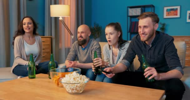 Czterech dobrych przyjaciół spędza wieczór w swoim towarzystwie, siedząc na kanapie w salonie, — Wideo stockowe