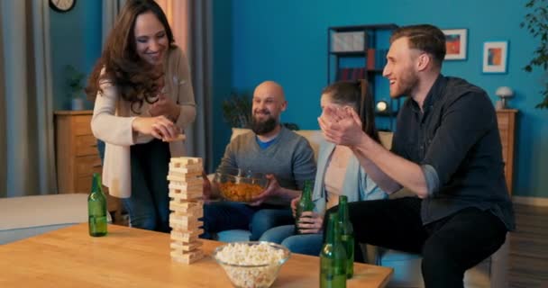 Vriendengroep speelt spel van het bouwen van toren van houten blokken in de avond, vrouw — Stockvideo