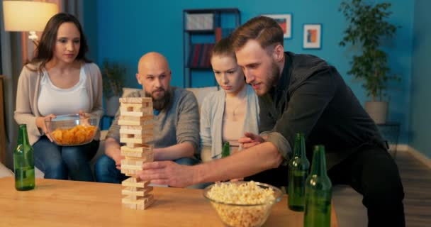 Fröhliche Gruppe von Freunden spielen Spiel des Stapelturms aus Holzklötzen am Abend, sie — Stockvideo