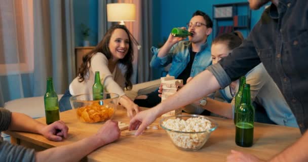 Vijf vrienden zitten rond kleine tafel met hapjes en drankjes in de avond in hun leven — Stockvideo