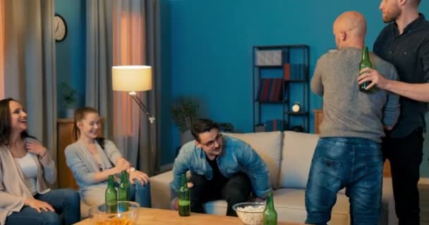 Quatro amigos sentados no sofá na sala de estar seu amigo vem visitar homens stand — Vídeo de Stock