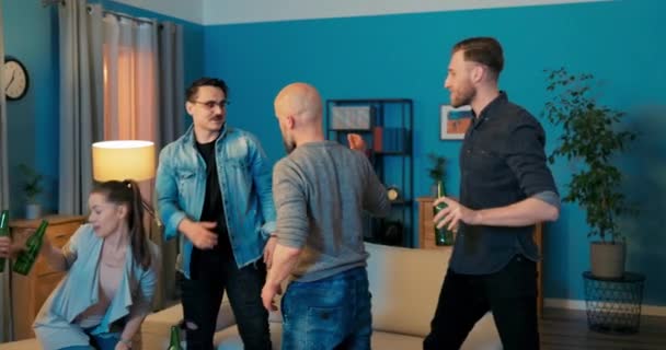 Vier vrienden zitten op de bank in de woonkamer hun vriend komt op bezoek mannen staan — Stockvideo