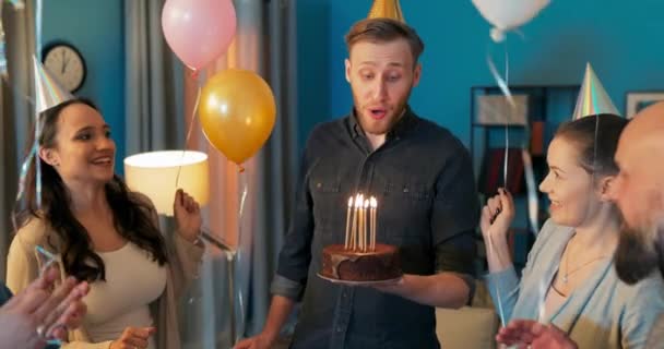 O aniversariante fica no meio da sala segurando um bolo de chocolate com — Vídeo de Stock