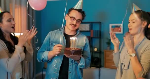 Festa di compleanno, ragazzo sta tenendo la torta con le candele accese in mano, soffiarli fuori, amici — Video Stock