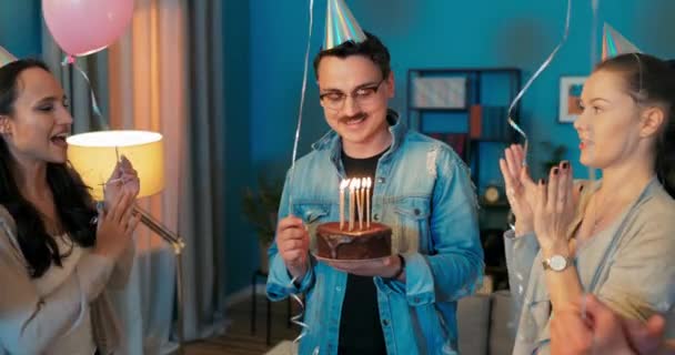 День народження, хлопчик тримає торт з палаючими свічками в руках, він робить — стокове відео
