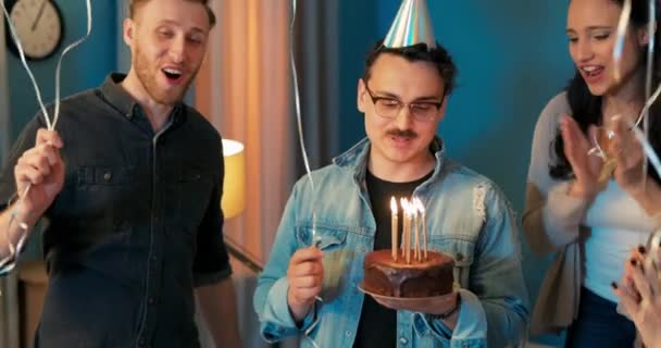 Fiesta de cumpleaños, un niño sostiene un pastel con velas encendidas en las manos, hace un — Vídeo de stock