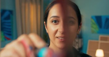 Yetenekli bir kadın, resme doğrudan bakıyor, gülümsüyor ve elinde bir resim tutuyor.