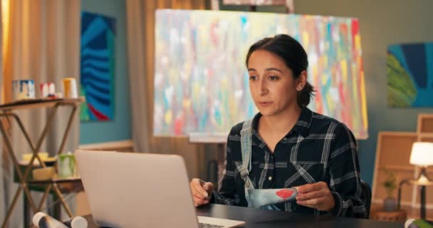 Ritratto di dipendente negozio d'arte, facendo attraverso il computer, laptop in diretta con i clienti del negozio, donna che mostra — Video Stock