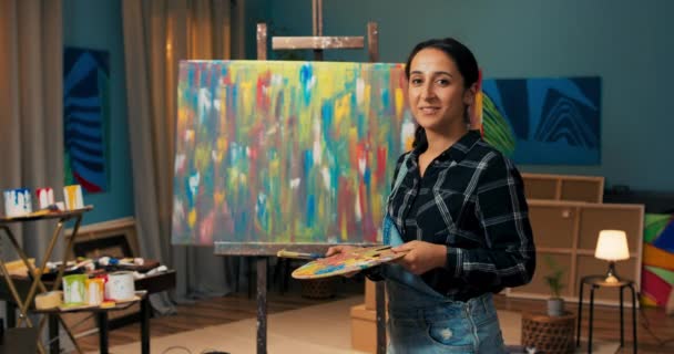 Mujer en sucio de pintura de mano sostiene pincel de pintura y paleta de madera para pinturas, sonrisa — Vídeos de Stock