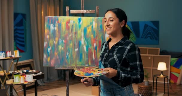Mujer en sucio de pintura de mano sostiene pincel de pintura y paleta de madera para pinturas, sonrisa — Vídeos de Stock